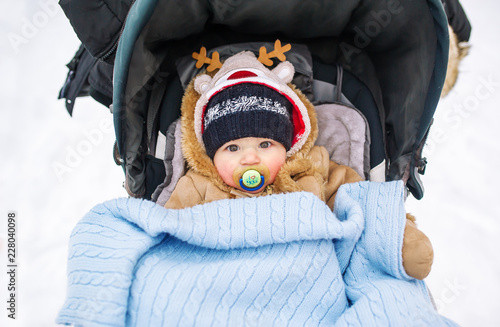 Obraz na płótnie Babywith a pacifier in a perambulator at a winter day. w salonie