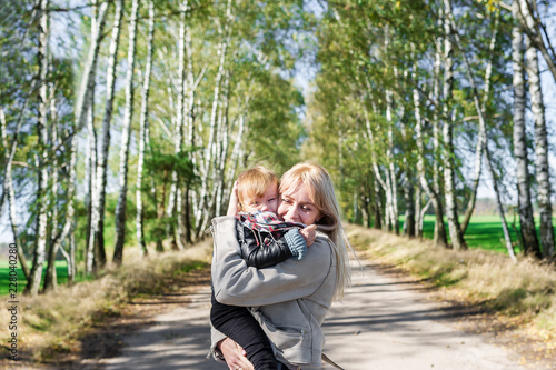 Young mother with her little baby daughter walking outdoors in a autumn park.