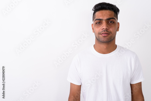 Young Indian man wearing white shirt against white background 