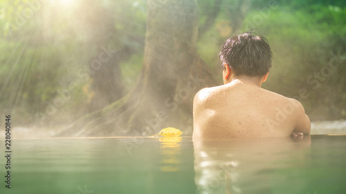 Asian man relaxing in morning is beautiful fog steam hot spring with sunlight  at Hin Dat Hot Spring   Kanchanaburi   Thailand