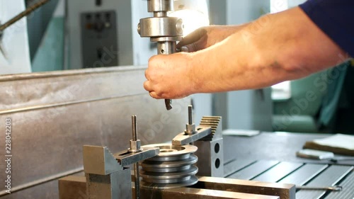 The man specialist checks the measuring tool with the size of drilling a metal pulley and inserts a drill into a drilling machine, individual entrepreneur photo