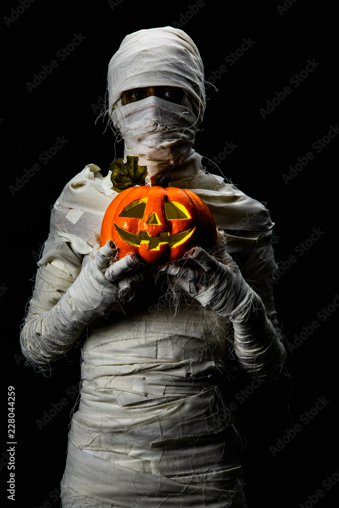 Studio shot portrait  of young man in costume  dressed as a halloween  cosplay of scary mummy pose like a hold jack'o pumpkin clamber acting on isolated black background