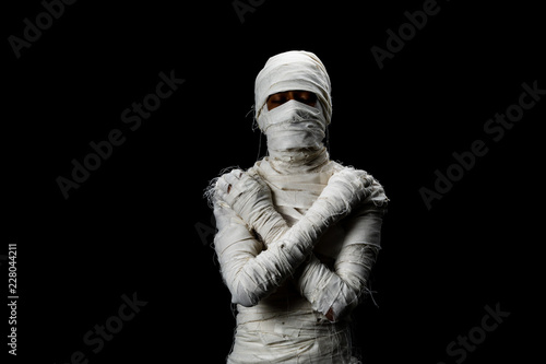 Valokuva Studio shot portrait  of young man in costume  dressed as a halloween  cosplay of scary mummy pose like close eye and cross his arm acting standing on isolated black background