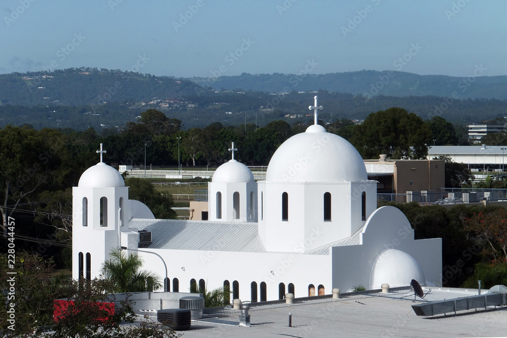 White Greek Orthodox Church with three crosses mountain hills in background