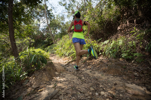 Young woman trail runner running on tropical forest trail © lzf