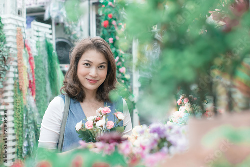 Beautiful Asian woman is buying flowers happily from the flower shop. Available in a variety of colors