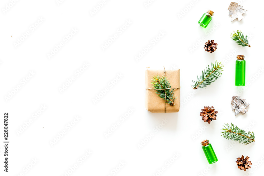 Composition with New Year gift wrapped in craft paper and decorted with pine sprout near pine sprigs, cones, spruce figure, fir oil on white background top view space for text Composition with New Year gift wrapped in craft paper and decorted with pine sprout near pine sprigs, cones, spruce figure, fir oil on white background top view space for text