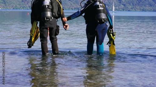 Two Scuba divers in a complete set for immersion, go to the water. Professional diving. 4K photo