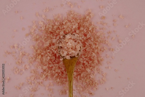 Sea bath salt.pink sea salt in a wooden spoon  on a light pink background.Organic cosmetics concept