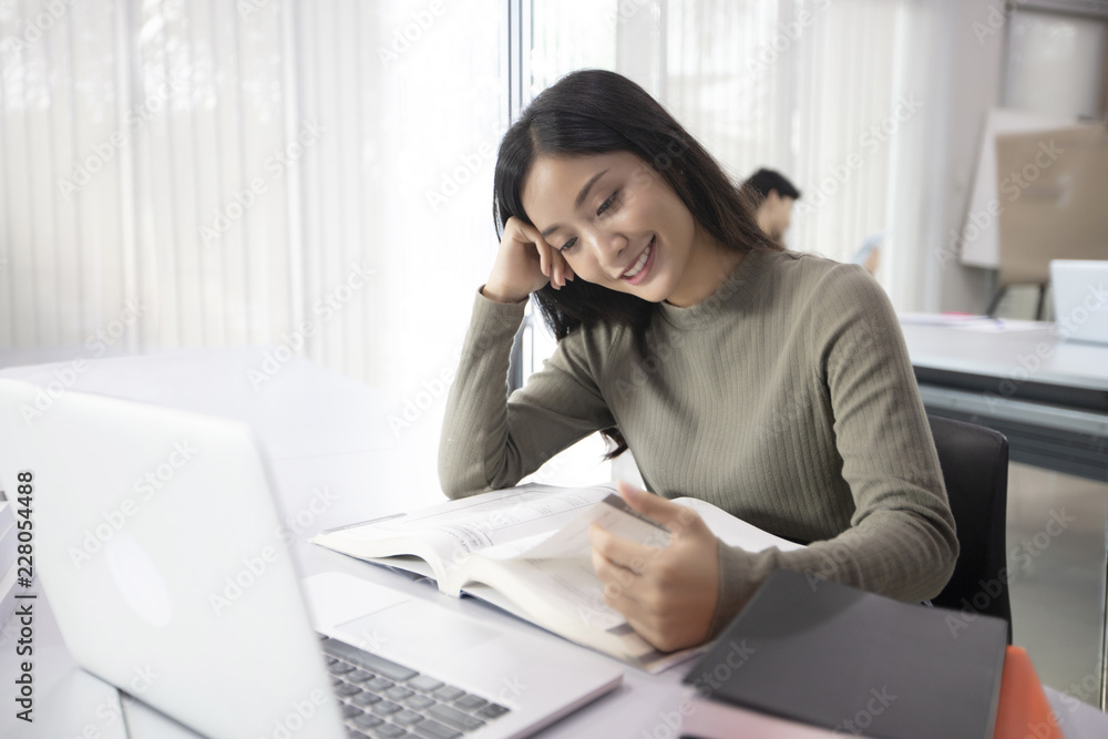 Asian women Students Smile and reading book and using notebook for helps to share ideas in the work and project. And also review the book before the exam Asian women Students Smile and reading book and using notebook for helps to share ideas in the work and project. And also review the book before the exam