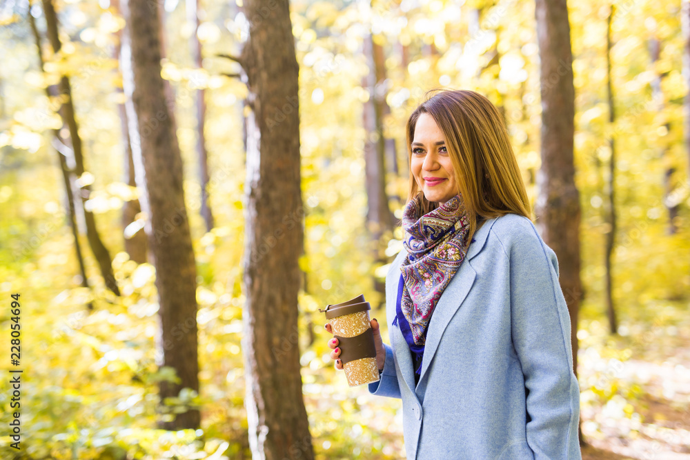 Attractive woman holding a cup of takeaway coffee cup on autumn street Attractive woman holding a cup of takeaway coffee cup on autumn street