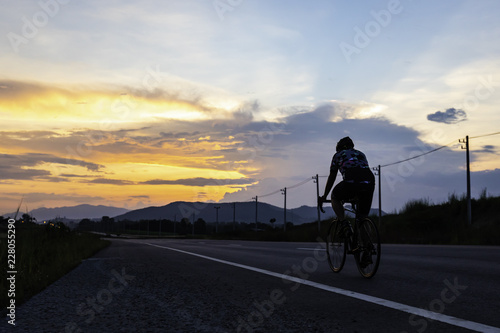 man riding bicycle on the highway at dusk
