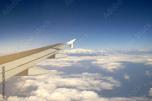 Wing of an Airplane Flying above the Cloud with View of Mount Everest Background, Travelling Concept