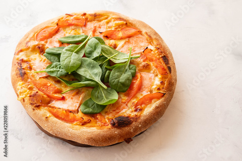 Traditional home made thin crust pizza with spinach, tomato, and mozzarella. Copy space.