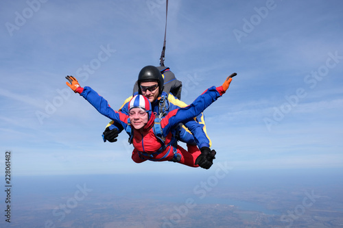 Tandem skydiving. Happy girl and her instructor are n the sky.