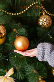 woman's hand holds orange ball on the background of other toys on the Christmas tree. New Year. Close-up