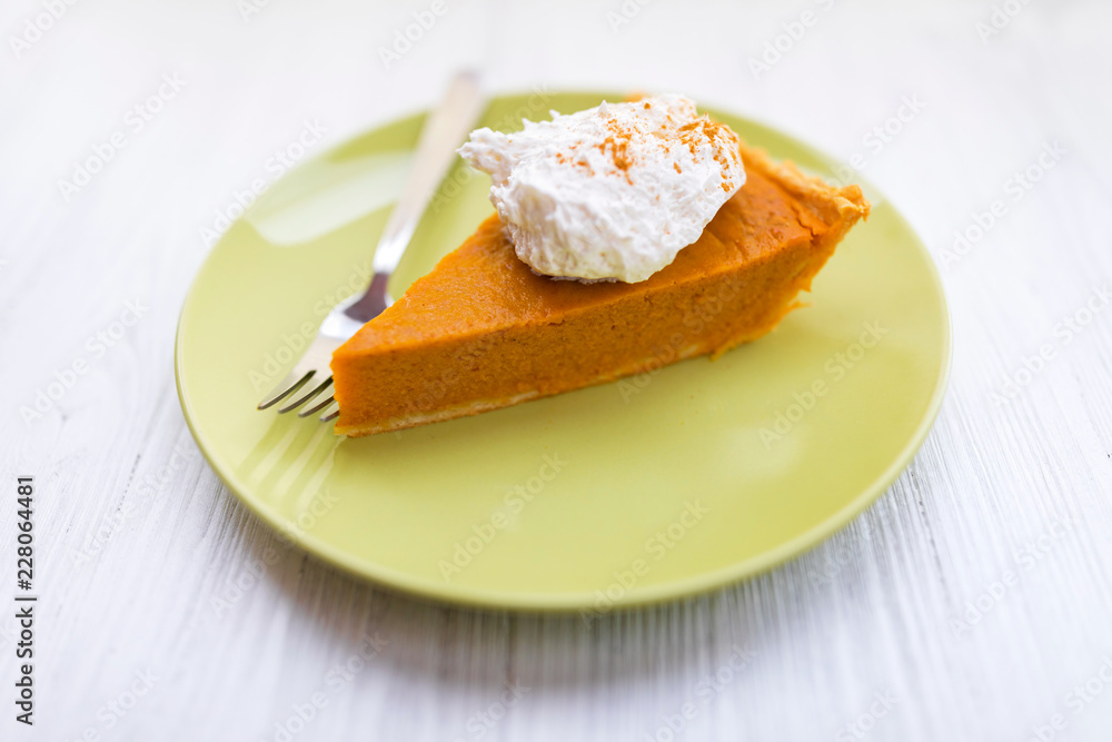 Slice of pumpkin pie with whipped cream over white wooden background Slice of pumpkin pie with whipped cream over white wooden background