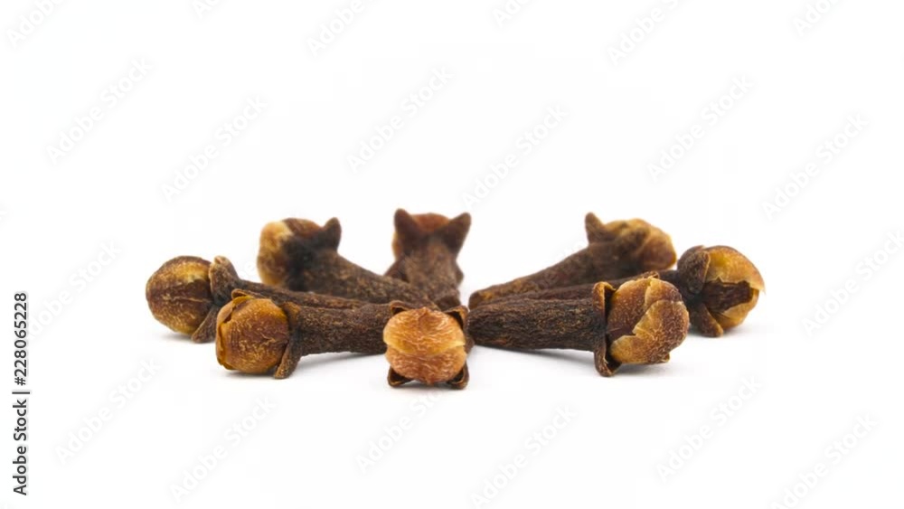 Star shaped pile of dried cloves. Rotating on the turntable. Isolated on the white background. Close up. Macro. Star shaped pile of dried cloves. Rotating on the turntable. Isolated on the white background. Close up. Macro.