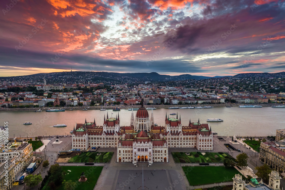 Fototapeta premium Budapest, Hungary - Aerial panoramic view of the Parliament of Hungary at sunset with beautiful dramatic purple clouds and sightseeing boats on River Danube