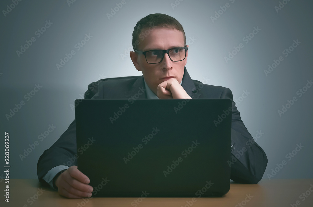 Pensive businessman is working with laptop computer and is thinking.