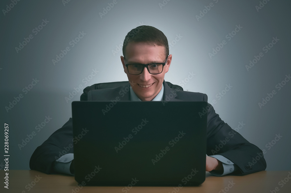 Happy businessman is working with laptop computer and is sitting by the table in the office. Happy businessman is working with laptop computer and is sitting by the table in the office.