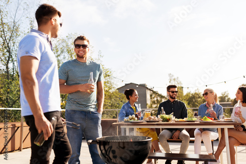 leisure and people concept - happy friends having barbecue party on rooftop
