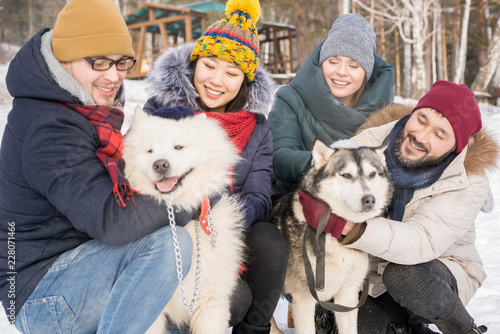 Photography Portrait of two happy couples playing with beautiful dogs outdoors while enjoyin