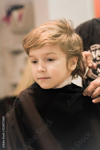 Pensive little boy at hairdresser's.