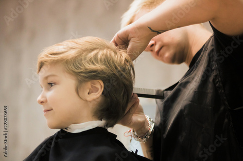 Smiling boy during haircut at hairdresser's.