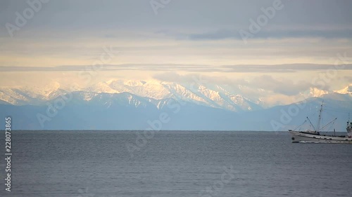 Fishing boat sailing on lake Baikal on the background of the Khamar Daban ridge photo