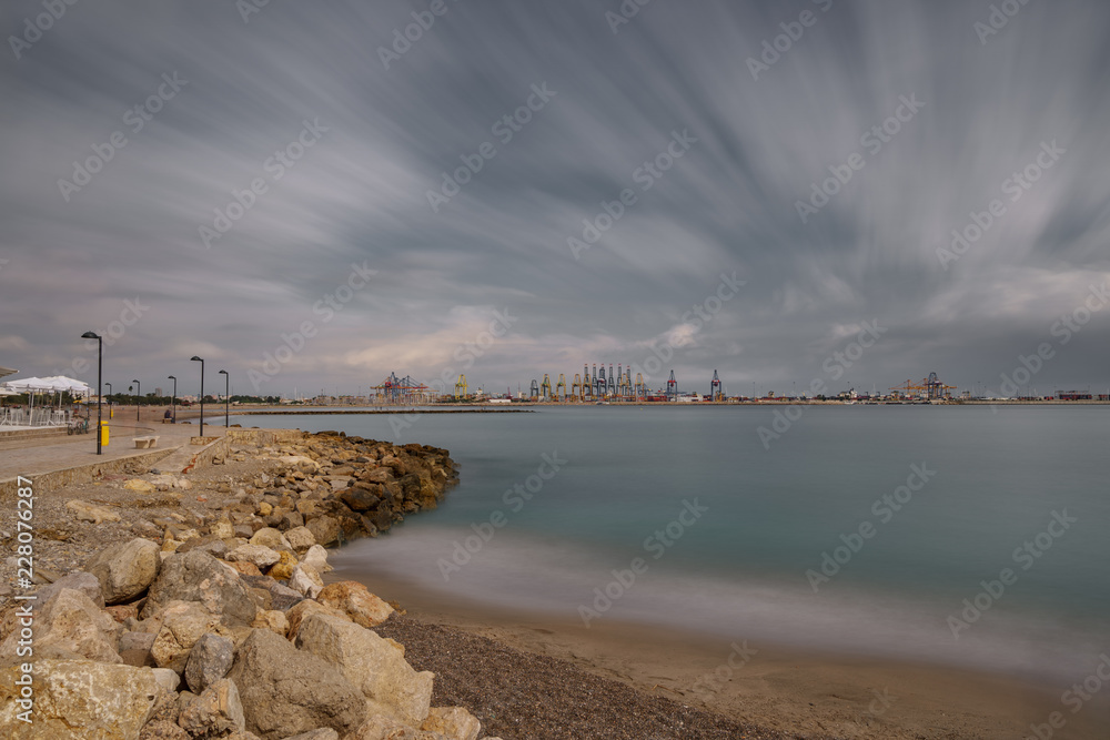Sea and commercial port with cranes, ultra long exposure in Valencia