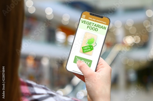 Vegetarian food idea, girl with frameless phone on blurred mall background
