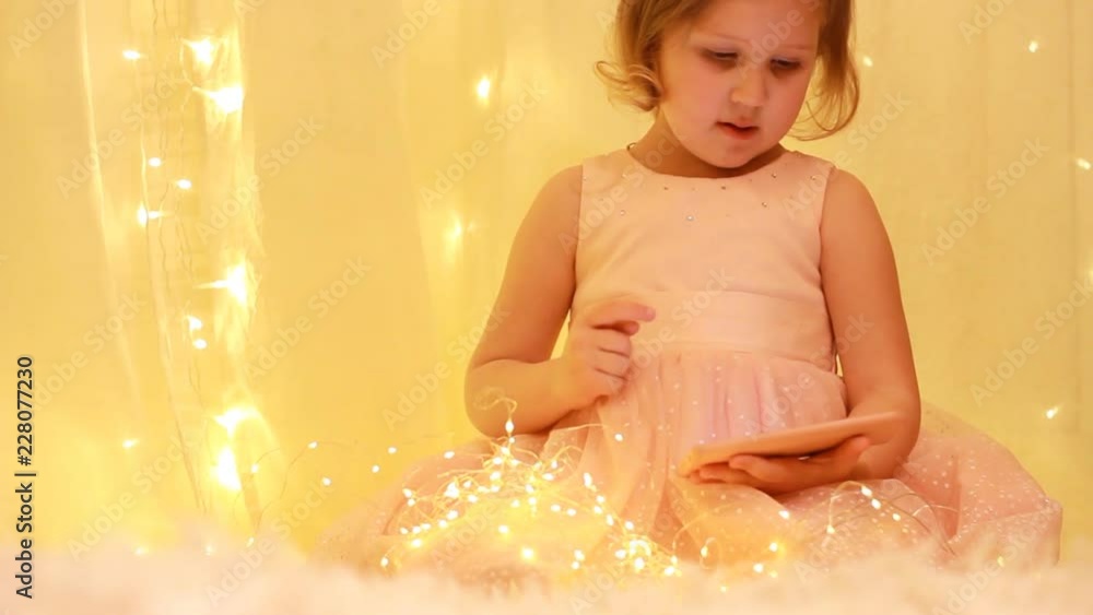 Child girl looking on the mobile phone screen and playing downloaded application. Child girl looking on the mobile phone screen and playing downloaded application.