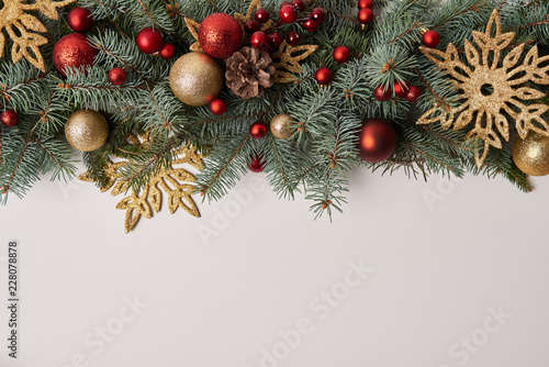top view of fir twigs with Christmas toys and golden snowflakes isolated on white