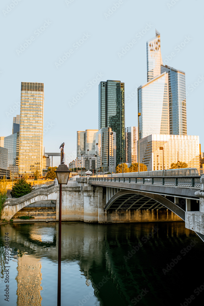 Naklejka premium Cityscape view of La Defense financial district with skyscrapers and old bridge during the morning light in Paris