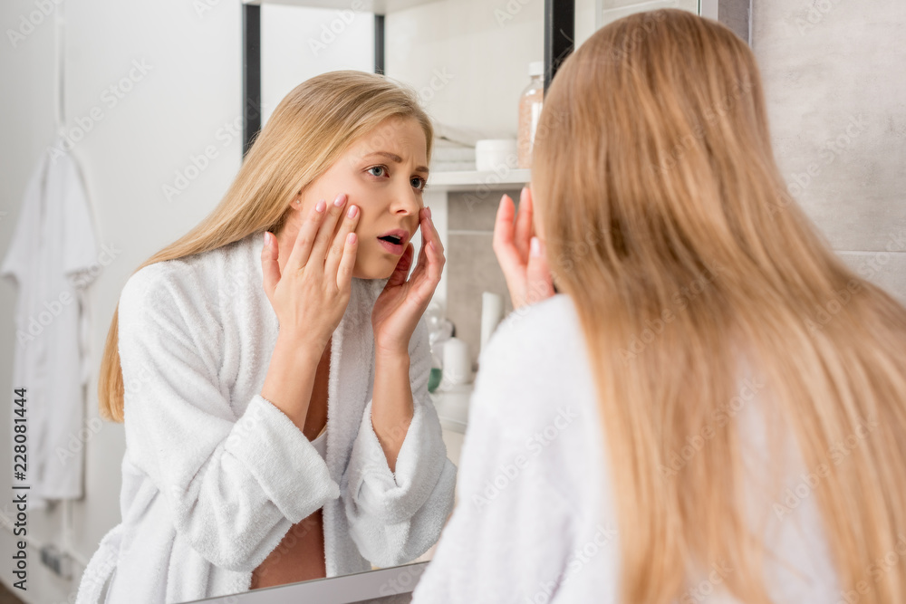 adult pregnant woman with skin problems looking at her face through mirror in bathroom adult pregnant woman with skin problems looking at her face through mirror in bathroom