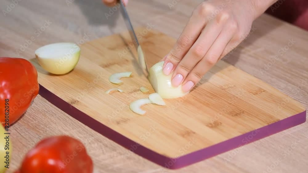 Woman cutting white onion with knife. Woman cutting white onion with knife.