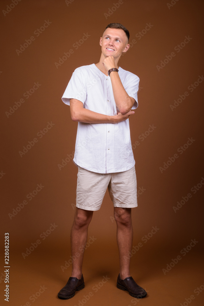 Young man wearing white shirt against brown background Young man wearing white shirt against brown background
