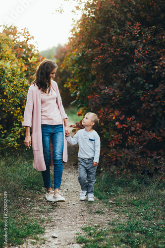 Happy family on autumn walk! Mother and son walking in the Park and enjoying the beautiful autumn nature. © galina_kovalenko