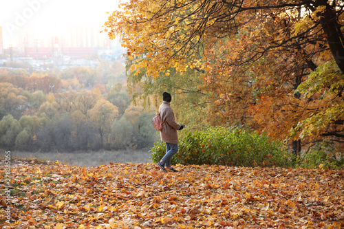 Student with a phone in his hand on the background of a autumn Park. © zinovskaya
