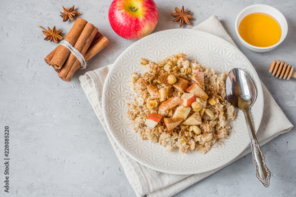 Fototapeta premium Oatmeal with fresh apples, nuts and cinnamon for Breakfast on the table, close-up, horizontal
