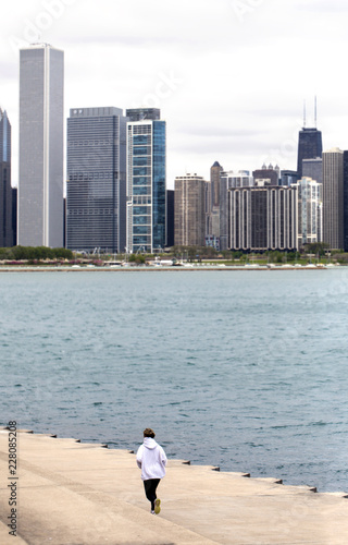 Female runner by Michigan lake in a cold cloudy day.  Chicago skyline in the background. Picture taken at Chicago Lakefront close to Adler Planetarium.