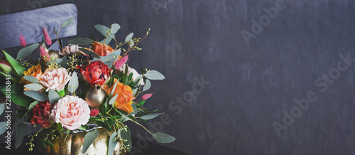 Autumn floral bouquet in punpkin vase on black chair, banner