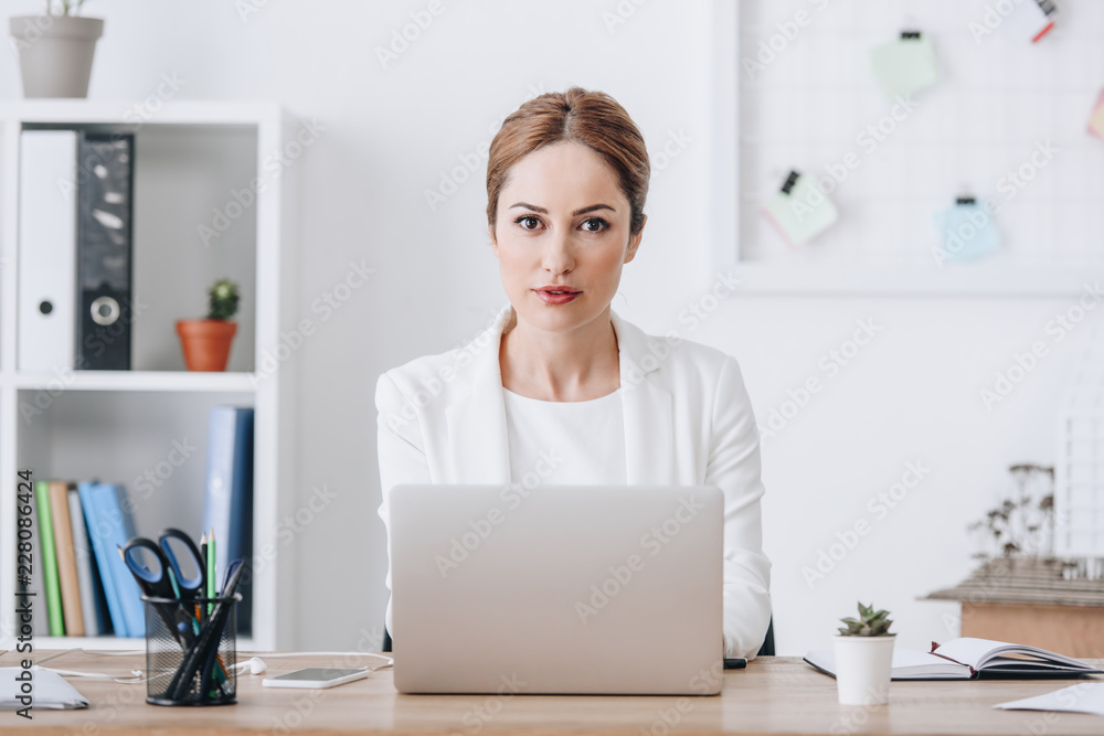 confident businesswoman in formal wear working with laptop in office