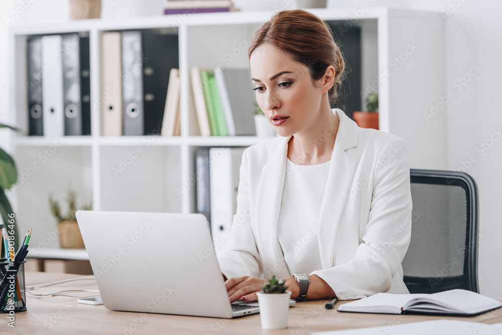 serious professional businesswoman in formal wear working with laptop in office serious professional businesswoman in formal wear working with laptop in office