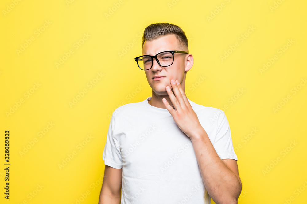Close up portrait of thoughtful man who looks away touching his chin and weighs the pluses and minuses of the offer isolated on t yellow background Close up portrait of thoughtful man who looks away touching his chin and weighs the pluses and minuses of the offer isolated on t yellow background
