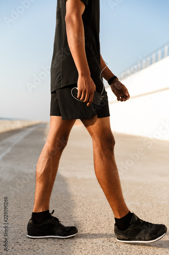 Young guy sportsman outdoors on the beach running walking.