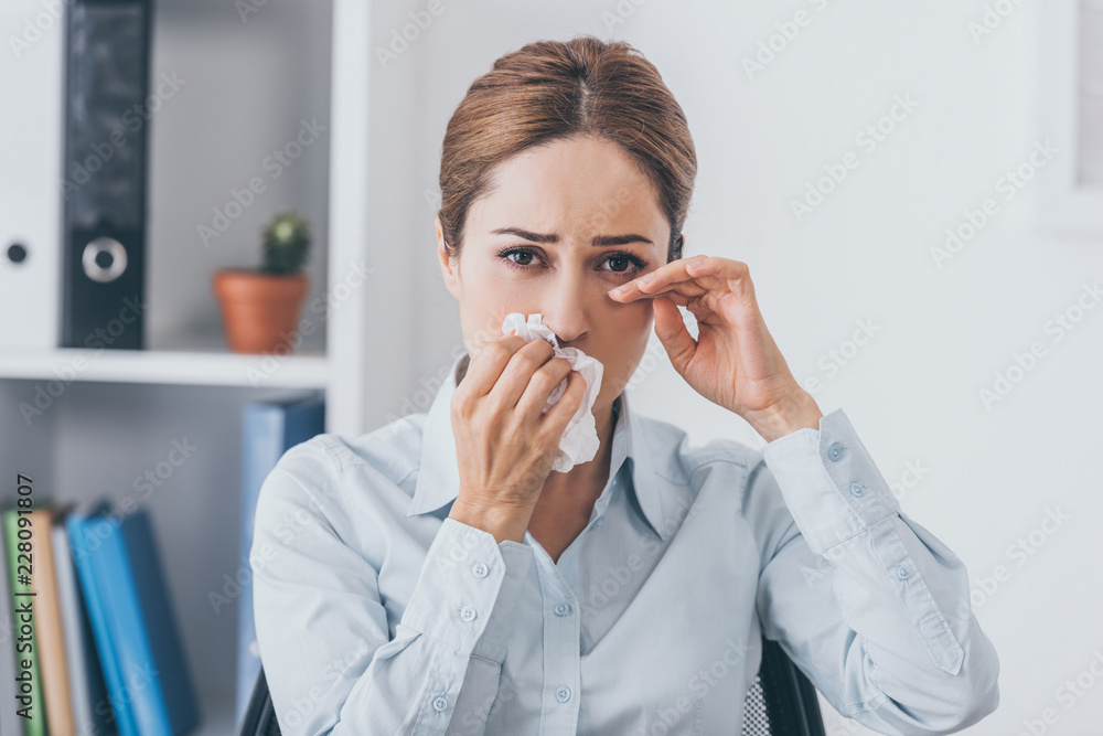 crying adult businesswoman with paper napkin sitting at office and looking at camera crying adult businesswoman with paper napkin sitting at office and looking at camera