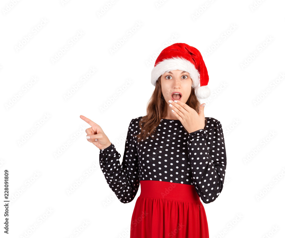 Girl in dress surprise showing product. emotional girl in santa claus christmas hat isolated on white background. holiday concept Girl in dress surprise showing product. emotional girl in santa claus christmas hat isolated on white background. holiday concept