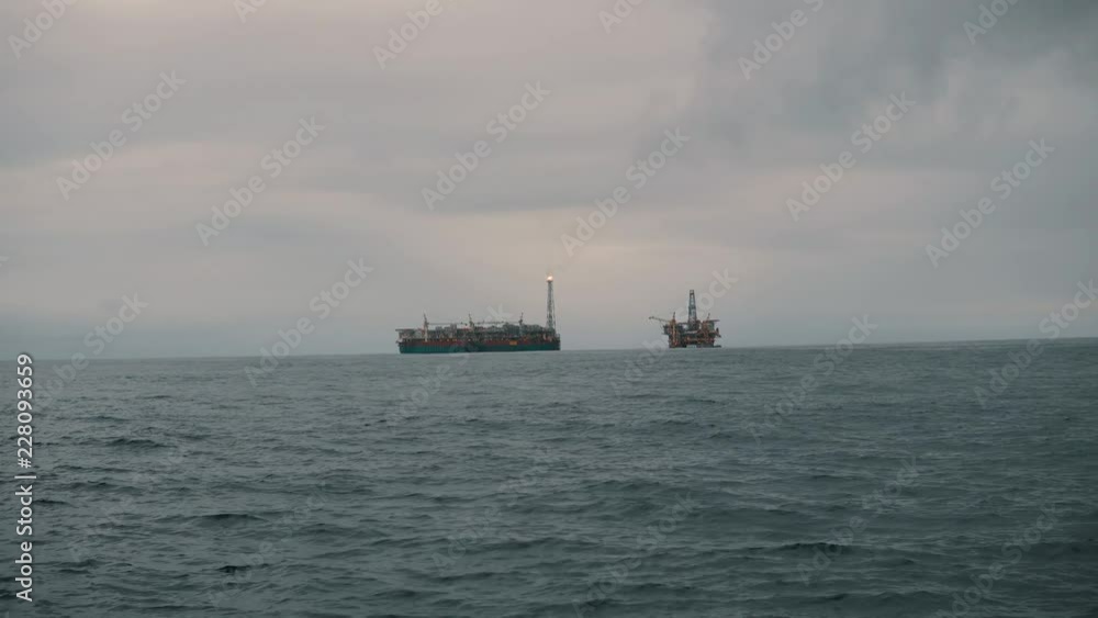 FPSO tanker vessel near Oil Rig platform. Offshore oil and gas industry. Flare is burning with smoke. Environmental pollution FPSO tanker vessel near Oil Rig platform. Offshore oil and gas industry. Flare is burning with smoke. Environmental pollution
